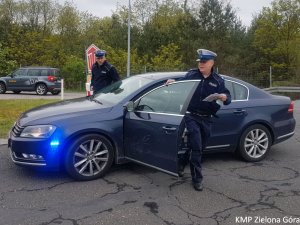 Zdjęcie kolorowe. Policjanci ruchu drogowego wysiadają z radiowozu nieoznakowanego marki Volkswagen Passat.