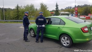 Zdjęcie kolorowe. Policjanci ruchu drogowego stoją przy samochodzie skoda Rapid i rozmawiają z kierującym