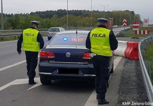 Zdjęcie kolorowe. Policjanci idą do radiowozu nieoznakowanego Volkswagen Passat.