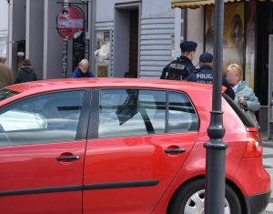 Policjanci rozmawiają z kobietą przy nieprawidłowo zostawionym samochodzie