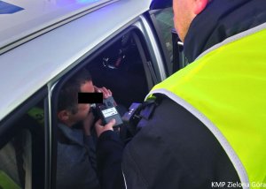 Policjant dokonuje pomiaru alkoholu w wydychanym powietrzu u mężczyzny