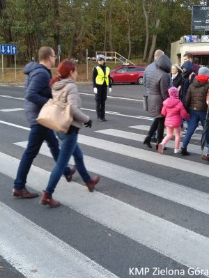Policjantka Ruchu Drogowego wstrzymuje ruch żeby piesi mogli przejść przez przejście dla pieszych