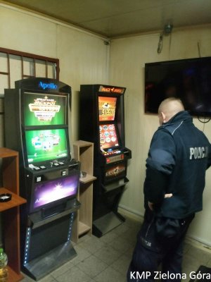 Policjant stoi przy dwóch zabezpieczonych automatach do gier