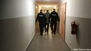 Policjanci prowadzący zatrzymanego mężczyznę przez korytarz