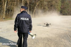 Policjant przy lądującym dronie.