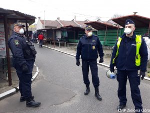 Policjant i dwóch Strażników Miejskich z megafonem na targowisku