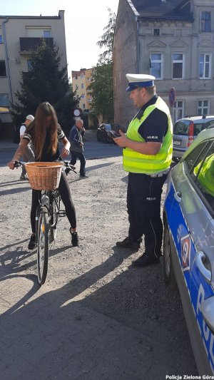 Policjant ruchu drogowego obok radiowozu rozmawia z rowerzystką