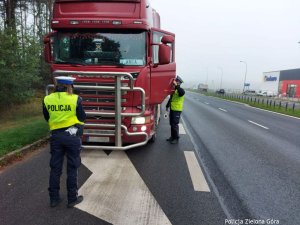 Dwóch funkcjonariuszy kontroluje czerwoną ciężarówkę