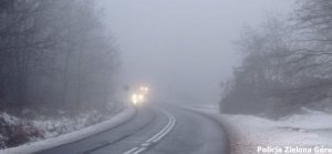 Zakręt na drodze podczas mgły, w oddali widać światła jadących samochodów