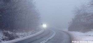 Zakręt na drodze podczas mgły, w oddali widać światła jadących samochodów
