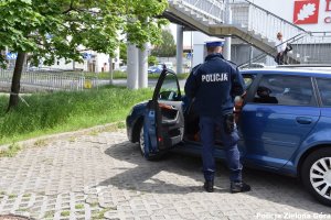 Policjant rozmawiający z kierowcą niebieskiego samochodu