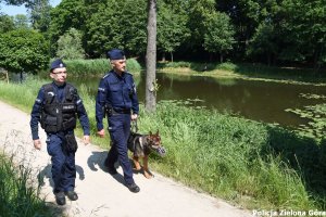 Dwóch policjantów i pies spacerujący nad zbiornikiem wodnym