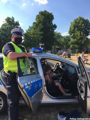 Policjant pilnujący dzieci za kierownicą radiowozu