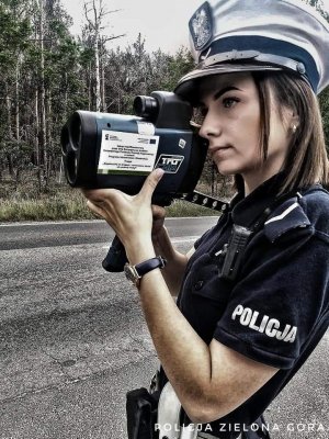 Policjantka trzymająca laserowy miernik prędkości.
